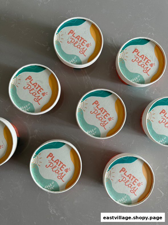 A top-down view of several colorful 'Plate & Play' branded containers on a grey surface.
