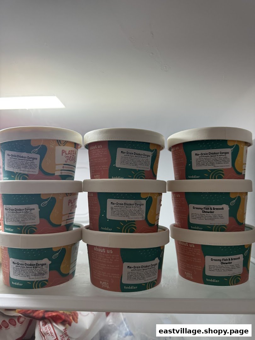 Containers of 'Plate & Play' toddler food, including congee and chowder, displayed in a fridge.