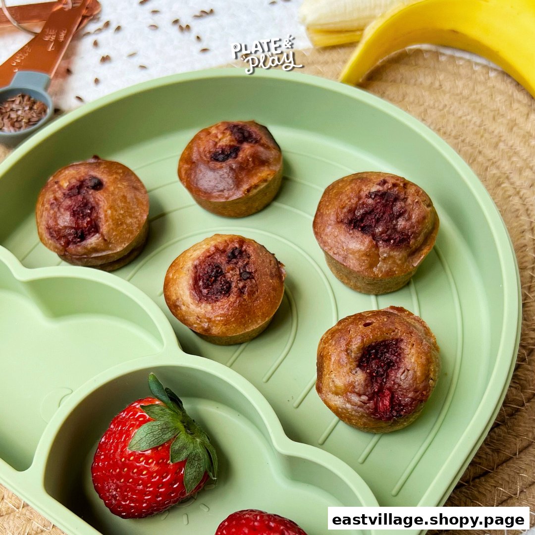 Mini fruit-filled muffins and fresh fruit on a green sectioned plate, showcasing healthy snacks.