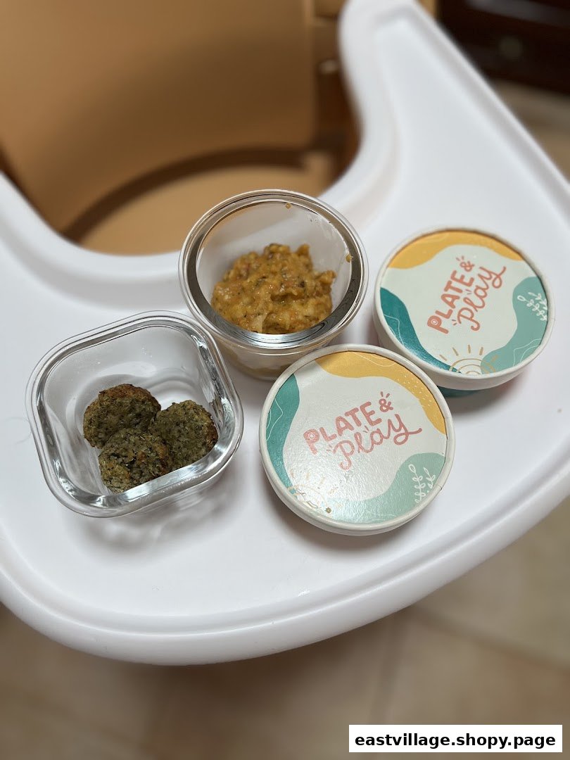 Portioned baby food from Plate & Play in containers on a high chair tray.