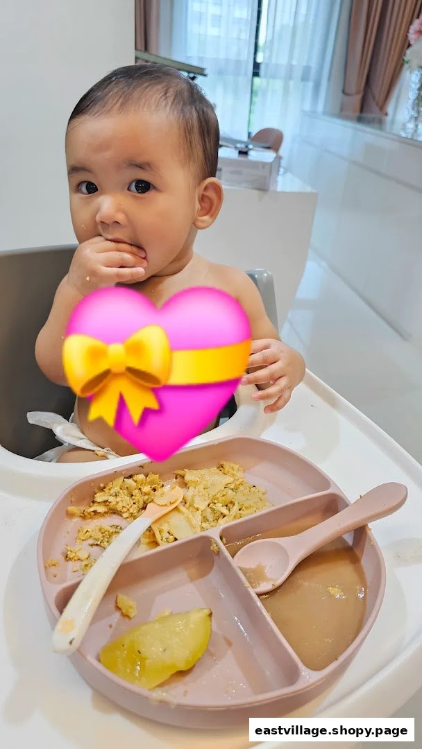 A baby in a high chair enjoys a meal from a divided plate.