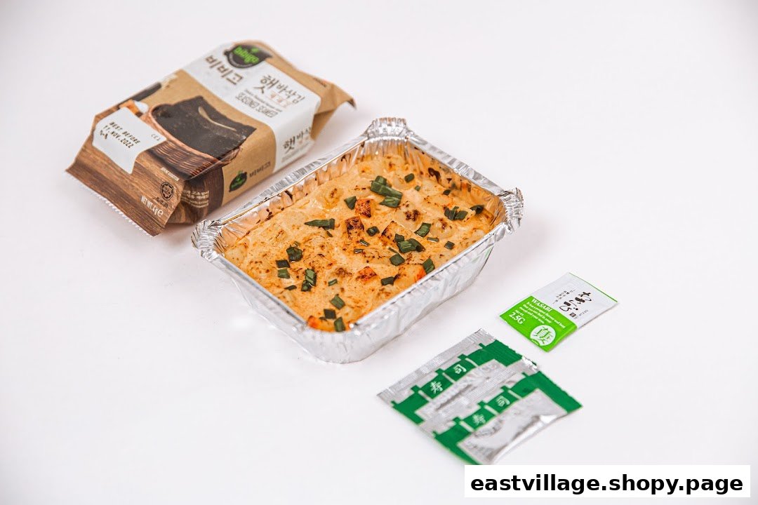 A baked rice dish in a foil container, accompanied by seasoned seaweed and condiment packets.