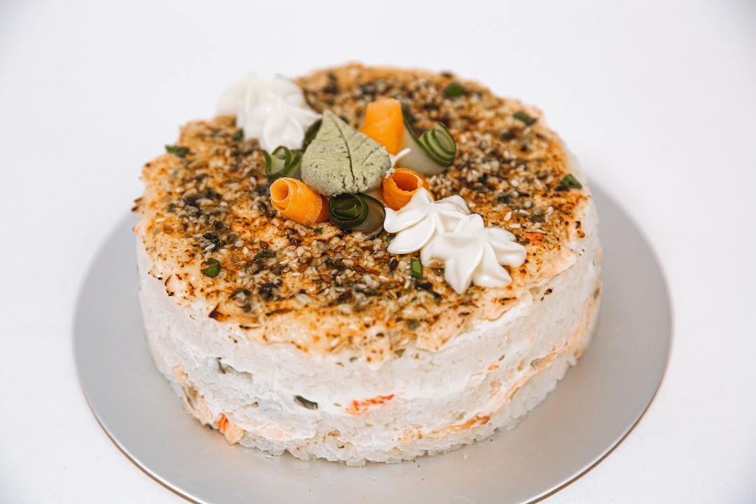 A beautifully decorated savory rice cake or sushi cake with various toppings and garnishes.