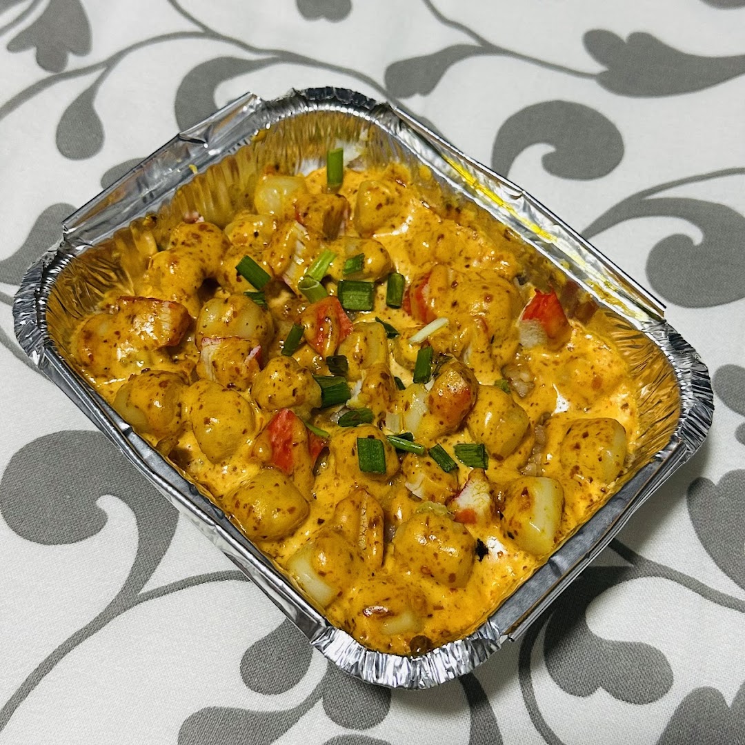 A delicious-looking dish featuring gnocchi or similar pasta in a rich, creamy sauce with crab sticks and green onions.