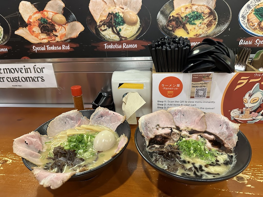 Two delicious bowls of ramen served on a counter, with menu displays and ordering instructions in the background.