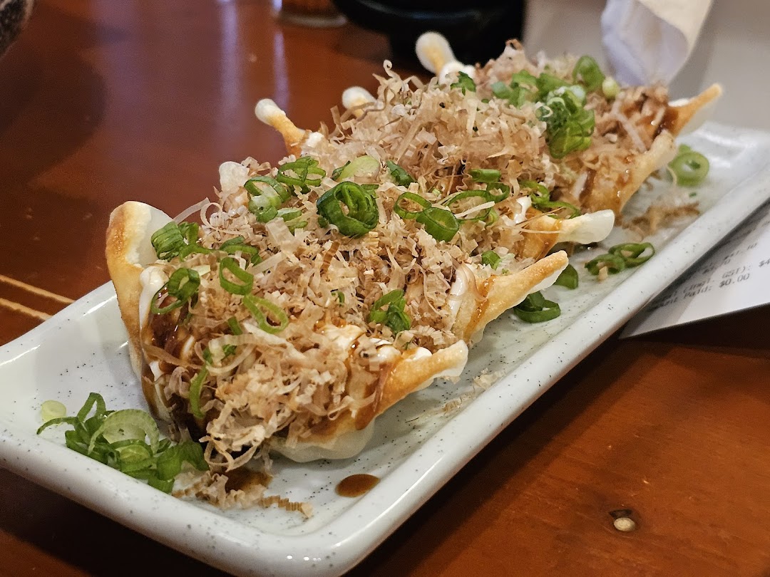 A plate of delicious gyoza topped with bonito flakes, green onions, and savory sauces at Ramen-ya.