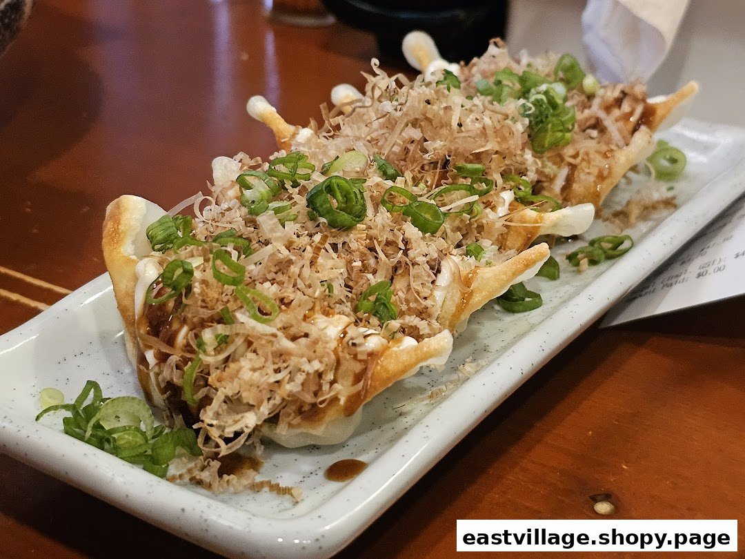 A plate of delicious gyoza topped with bonito flakes, green onions, and savory sauces at Ramen-ya.