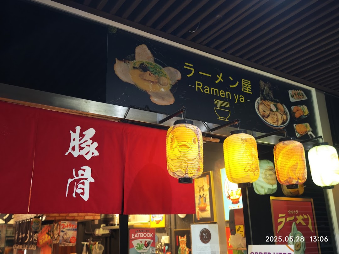 The vibrant entrance of Ramen-ya, featuring a red noren, Japanese lanterns, and delicious ramen visuals.