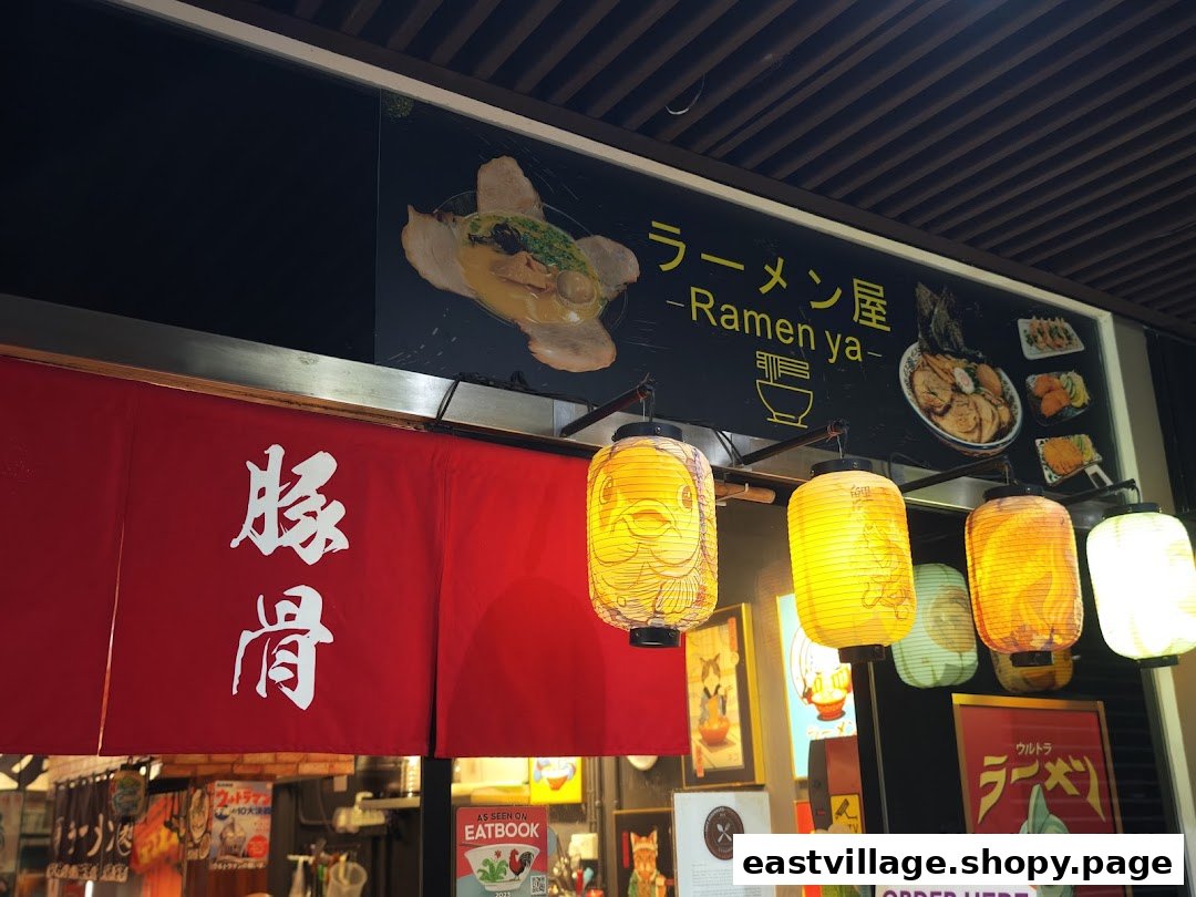 The vibrant entrance of Ramen-ya, featuring a red noren, Japanese lanterns, and delicious ramen visuals.