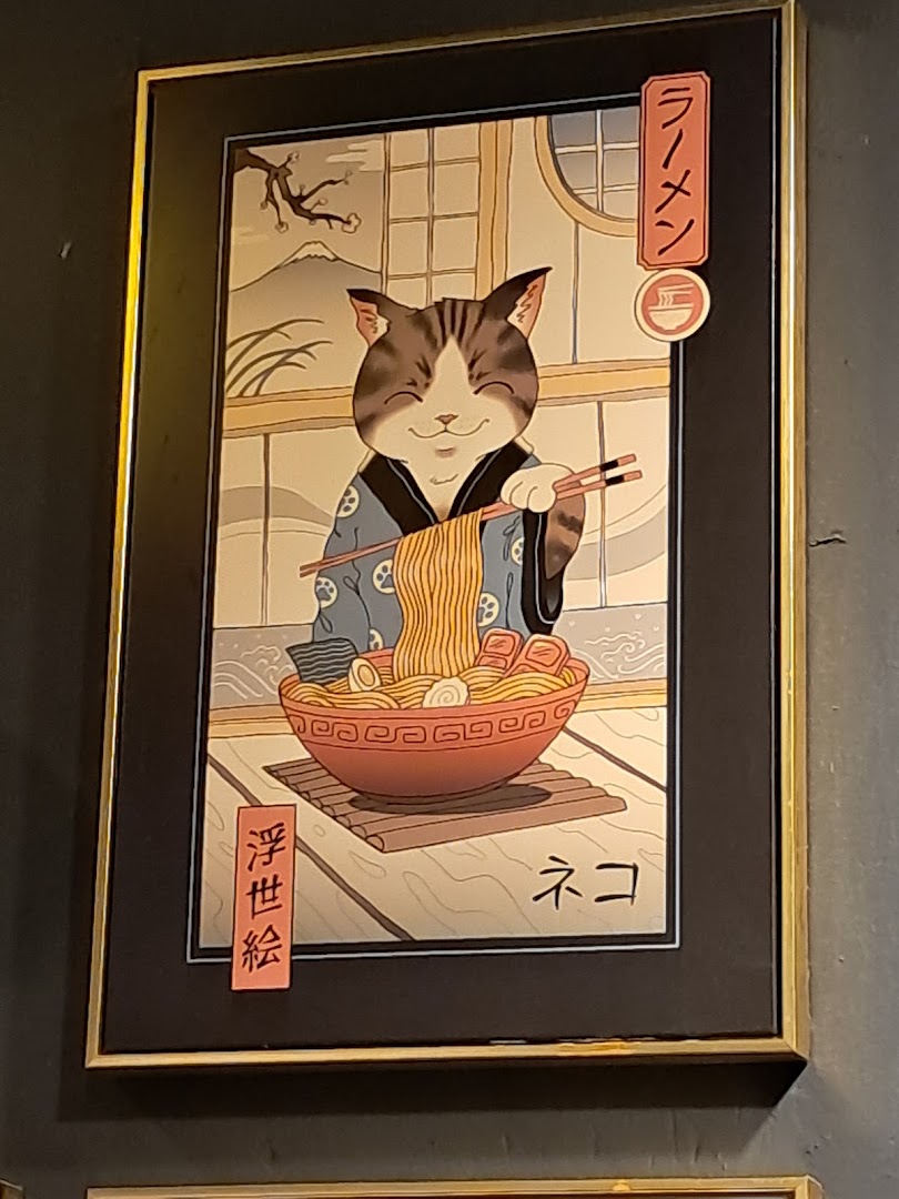 A framed artwork depicting a happy cat in traditional Japanese attire enjoying a bowl of ramen.