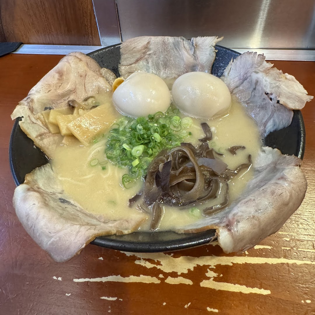 A close-up of a large, inviting bowl of ramen with pork slices, soft-boiled eggs, bamboo shoots, and mushrooms.