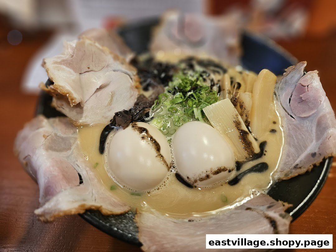 A close-up of a rich ramen bowl featuring tender pork slices, soft-boiled eggs, bamboo shoots, and green onions.