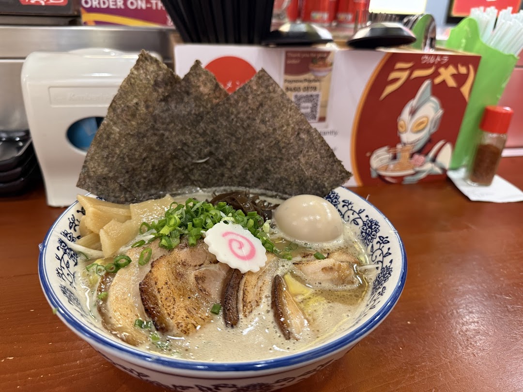 A close-up of a delicious bowl of ramen with chashu pork, egg, seaweed, and other toppings.