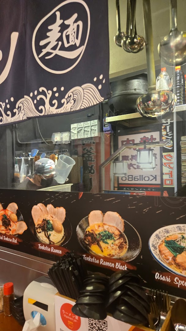 An interior view of Ramen-ya, showcasing delicious ramen dishes on display and a chef at work.