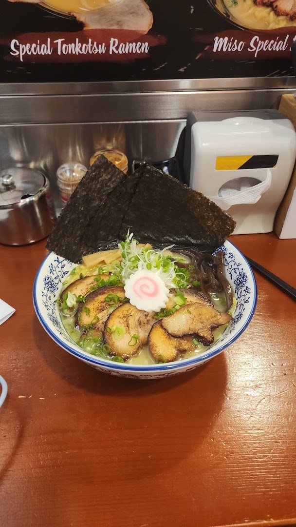A close-up of a delicious bowl of ramen with pork, seaweed, and narutomaki on a wooden table.