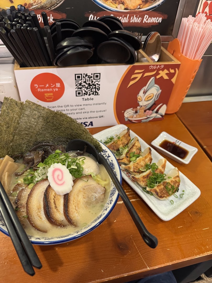 A delicious bowl of ramen and gyoza on a table, with a QR code for convenient ordering.