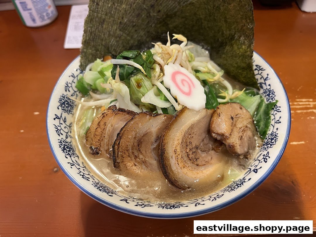 A close-up of a delicious bowl of ramen with pork belly, vegetables, and nori.