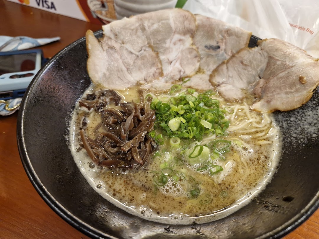 A close-up of a delicious bowl of ramen with pork slices, wood ear mushrooms, and green onions.