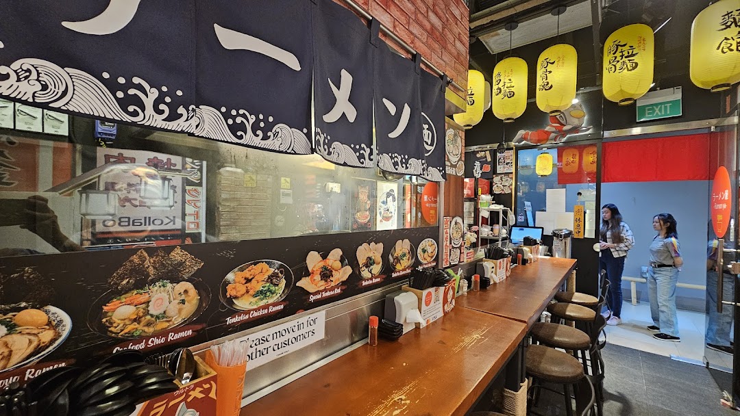 Cozy ramen shop interior with counter seating, kitchen view, and customers.