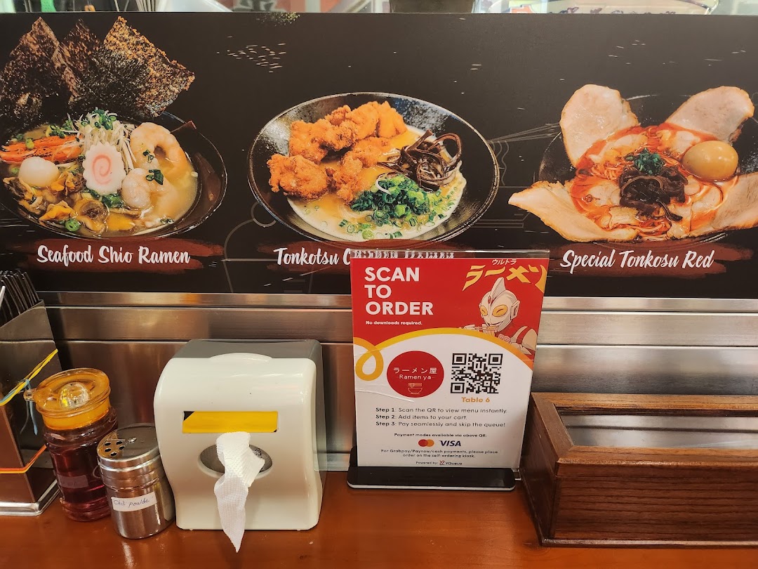 A display board showcasing various ramen dishes and a QR code for convenient mobile ordering at Ramen-ya.