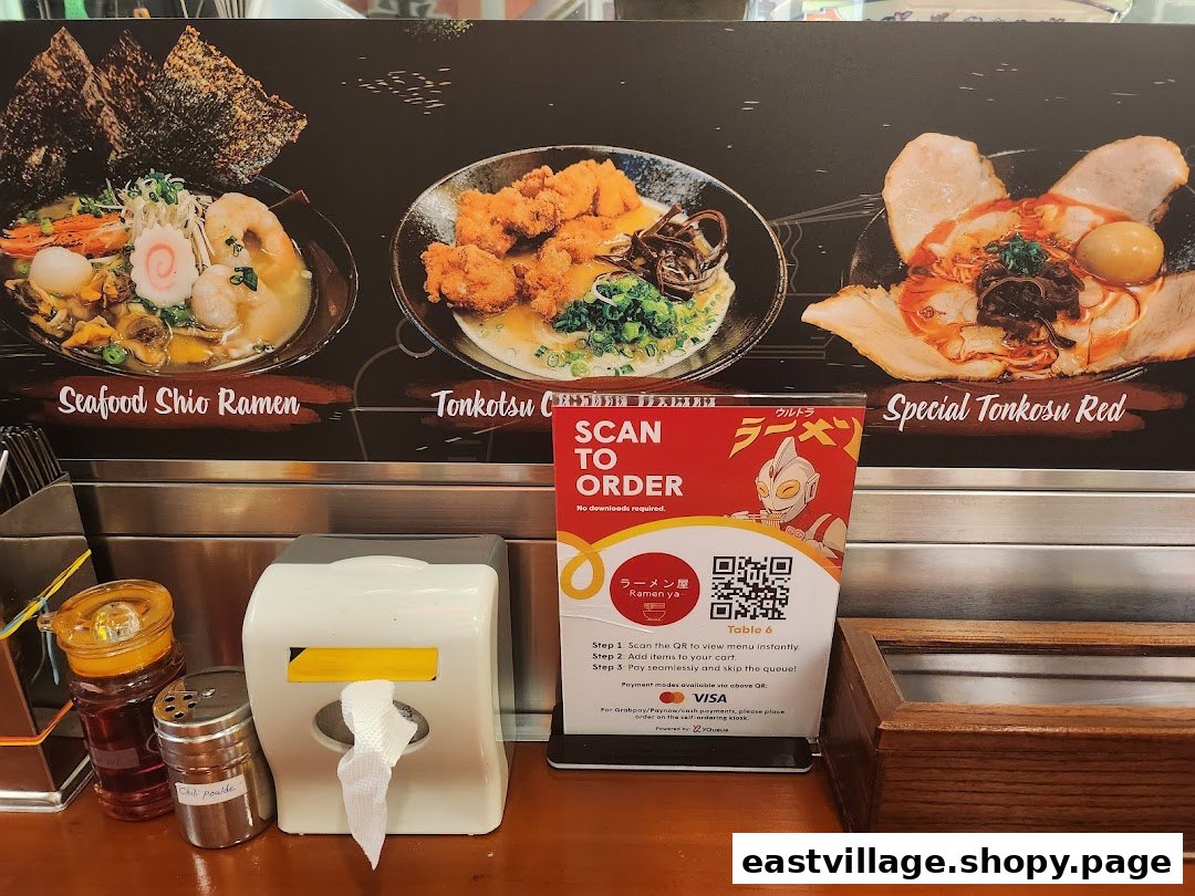 A display board showcasing various ramen dishes and a QR code for convenient mobile ordering at Ramen-ya.