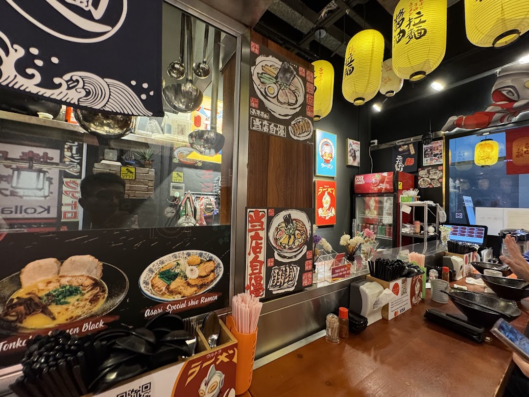 An inviting interior view of Ramen-ya, featuring counter seating, traditional decor, and food displays.