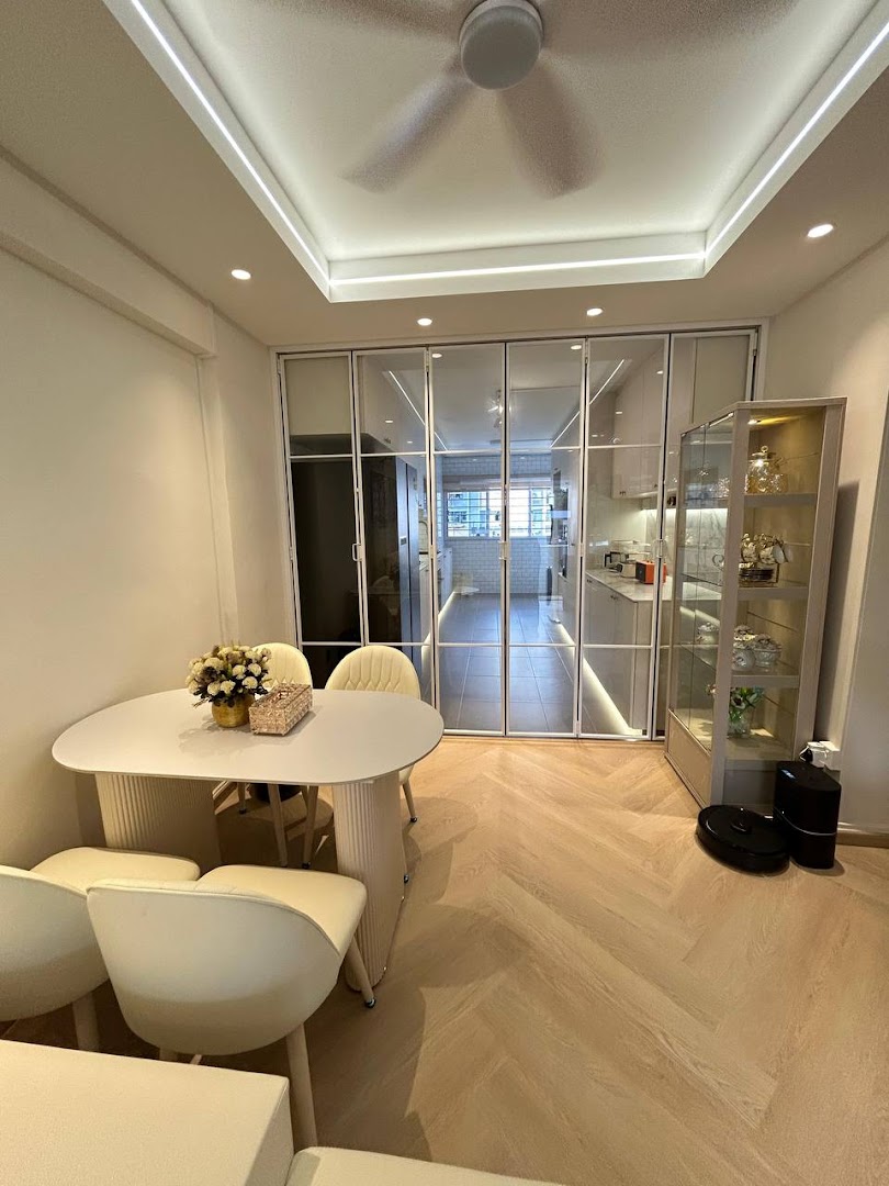 A modern dining area with light wood herringbone flooring, leading to a kitchen through glass panel doors.