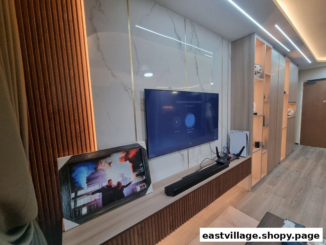 A modern living room setup featuring a large TV, soundbar, gaming console, and custom built-in cabinetry.