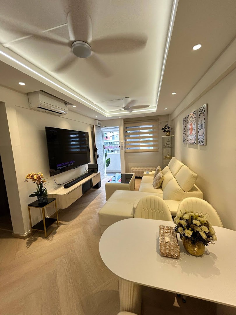 A modern, well-lit living room featuring a large sectional sofa, TV console, and dining area with light wood flooring.