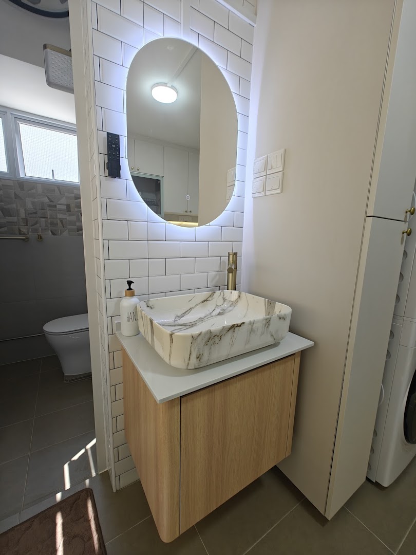 A modern bathroom features a stylish marble-patterned vessel sink, a wooden vanity, and an illuminated oval mirror.