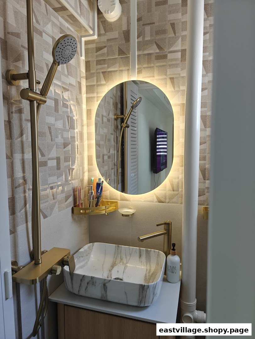 A modern bathroom interior featuring a marble vessel sink, gold fixtures, and an illuminated mirror.