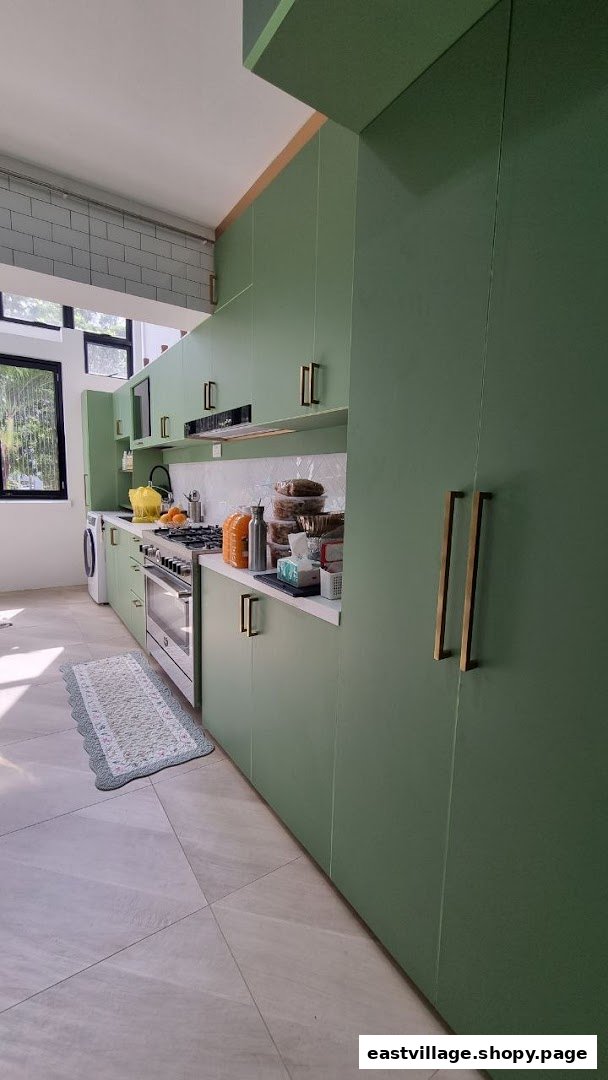A modern kitchen interior featuring sage green cabinets, white countertops, and stainless steel appliances.