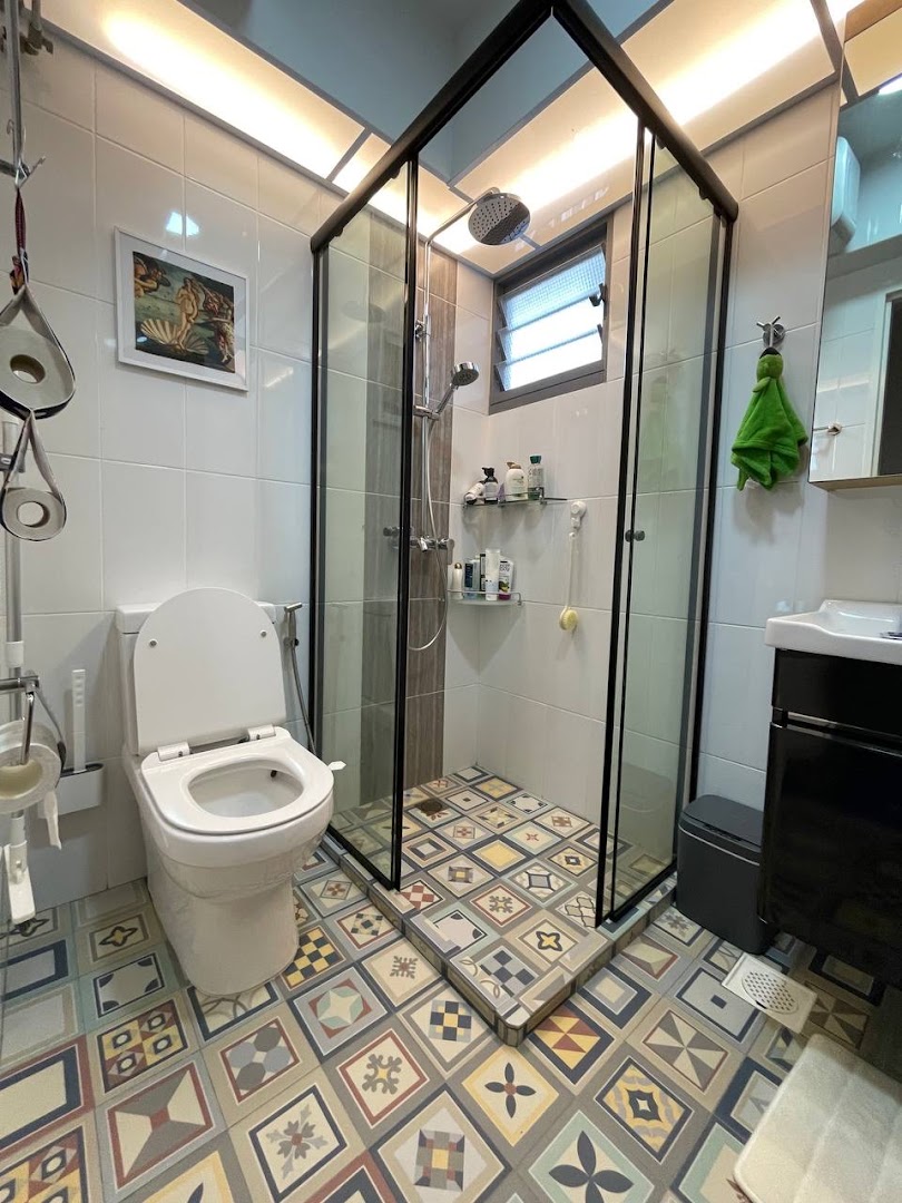 A modern bathroom featuring a sleek glass shower enclosure, a white toilet, and vibrant patterned floor tiles.