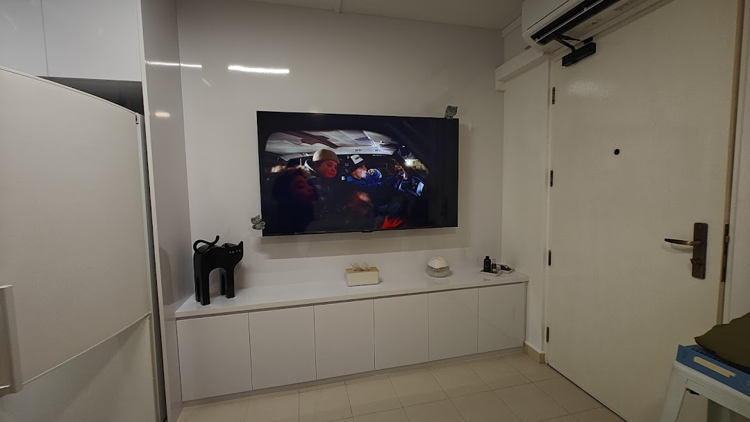 A modern, minimalist interior featuring a wall-mounted TV, sleek white cabinets, and a clean aesthetic.