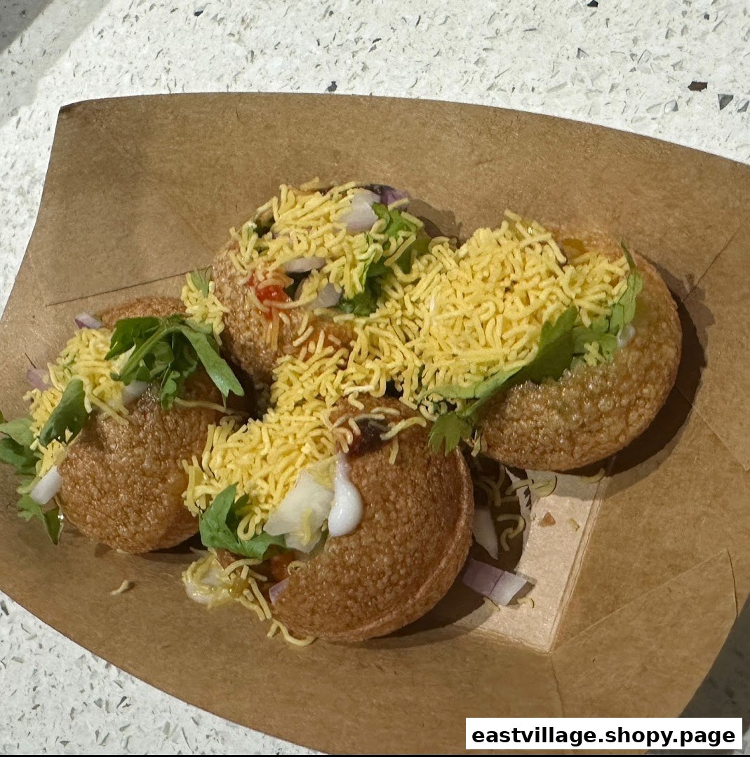 Close-up of delicious Indian street food, likely pani puri, served in a brown paper tray.