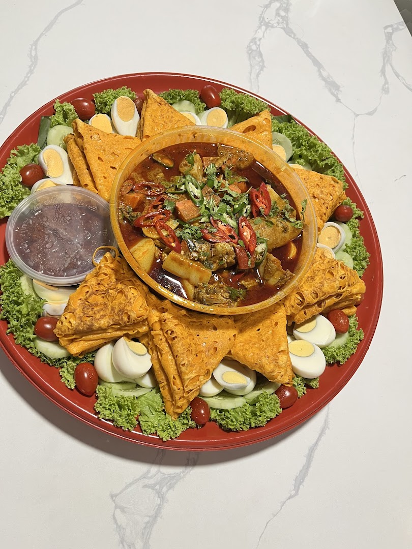 A vibrant platter with curry, roti jala, boiled eggs, fresh lettuce, tomatoes, and cucumber.