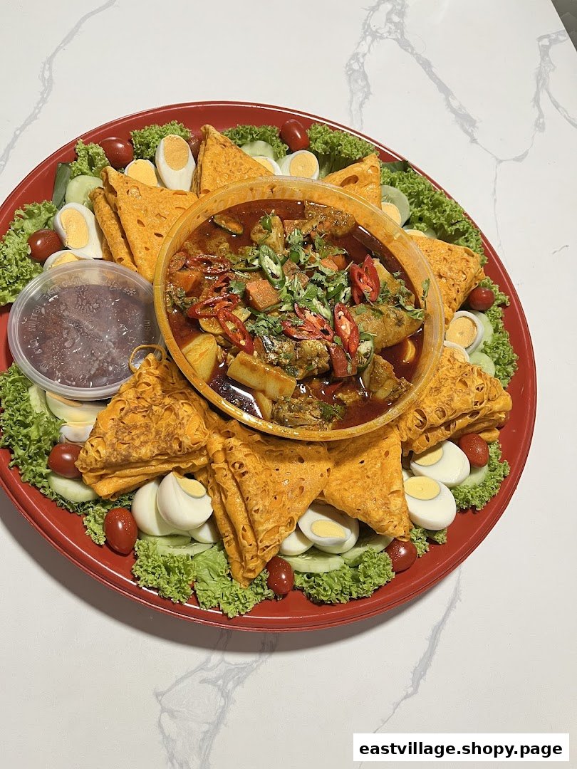 A vibrant platter with curry, roti jala, boiled eggs, fresh lettuce, tomatoes, and cucumber.