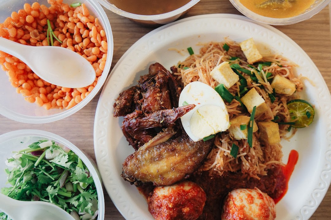 A close-up overhead shot of a delicious meal featuring noodles, fried chicken, eggs, and various side dishes.