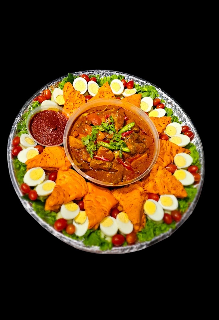 A vibrant food platter featuring a central curry, surrounded by savory pastries, boiled eggs, cherry tomatoes, and fresh lettuce.