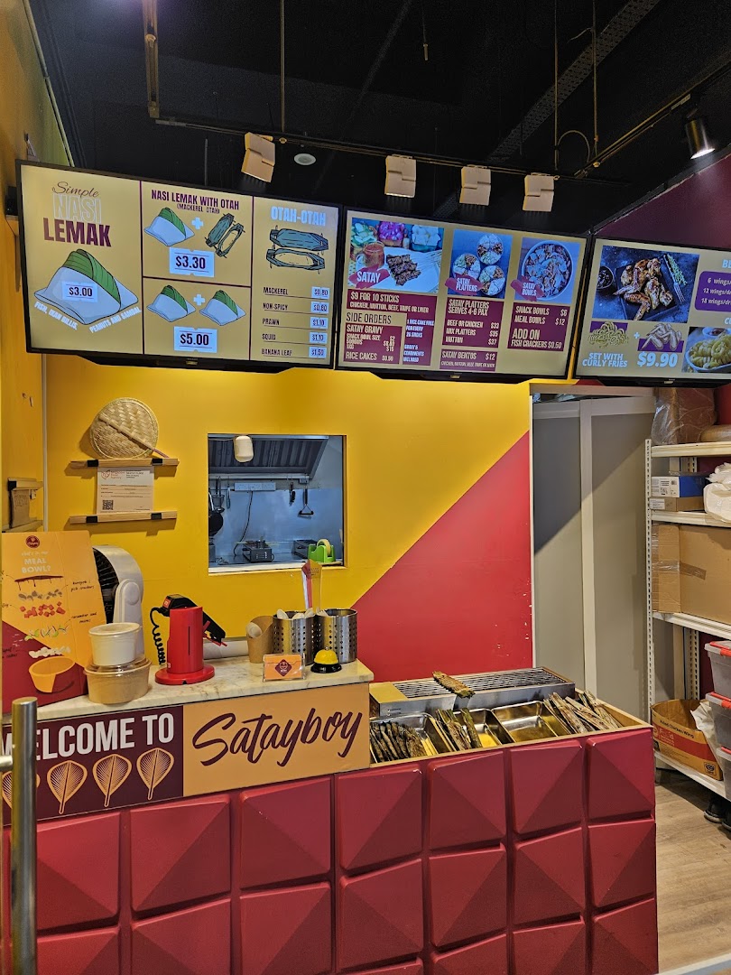 A vibrant counter and digital menu boards of Satayboy, showcasing their Malaysian cuisine.