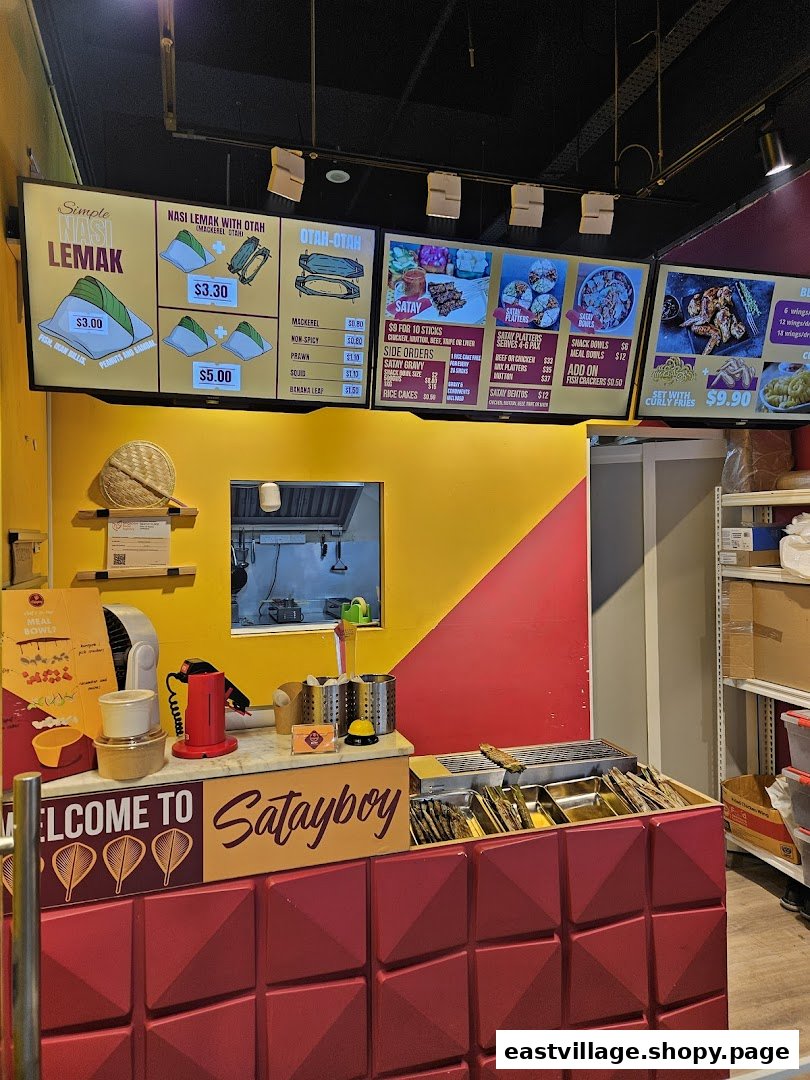 A vibrant counter and digital menu boards of Satayboy, showcasing their Malaysian cuisine.