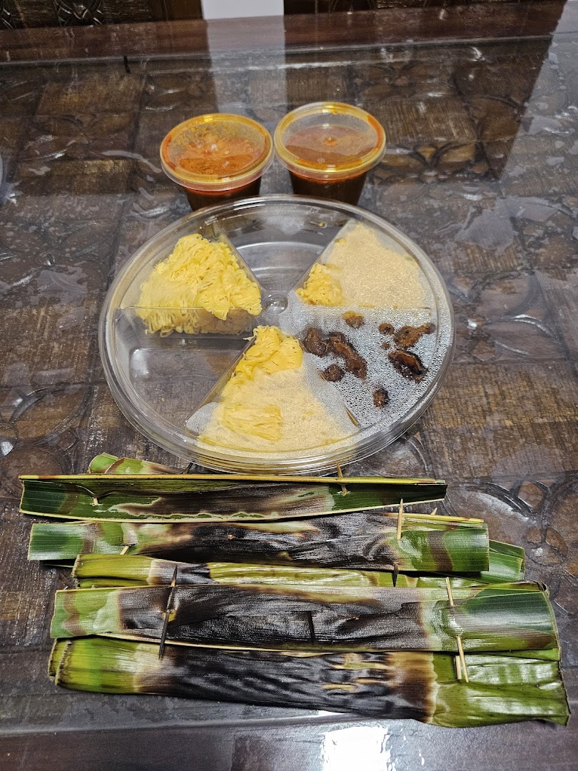 A close-up of various delicious Malaysian dishes, including grilled Otak-Otak and assorted desserts with sauces.