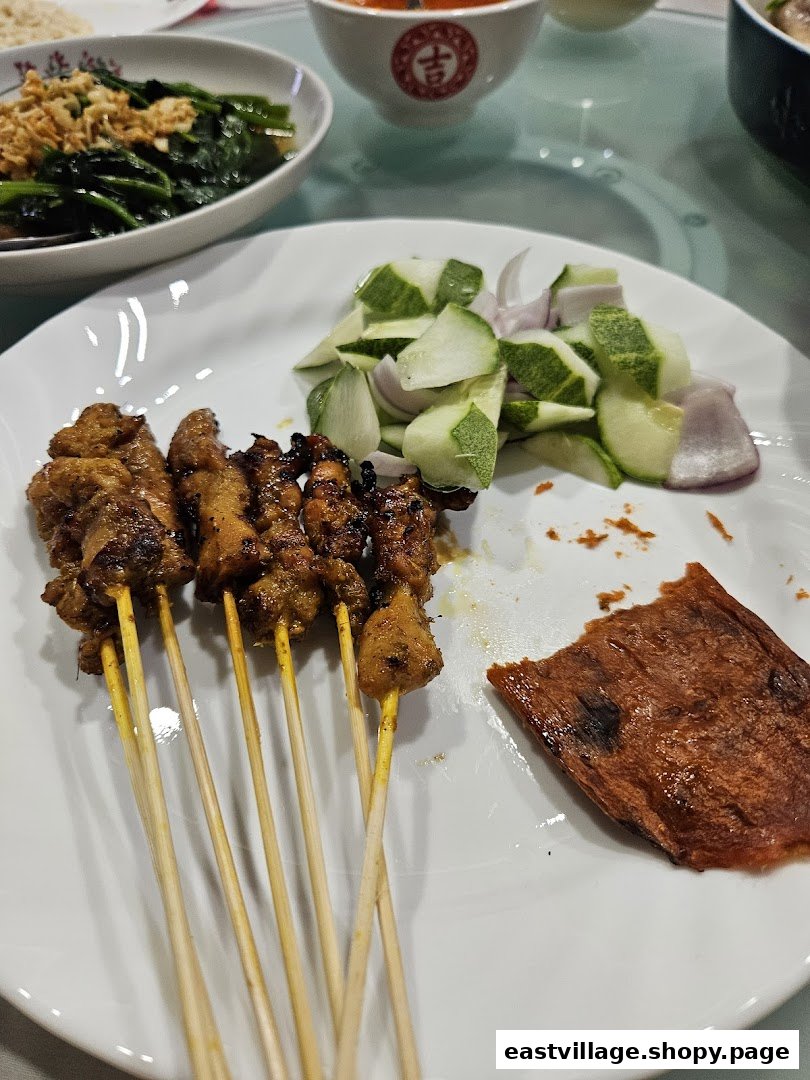 A plate of delicious satay skewers with fresh cucumber and onion, ready to be enjoyed.