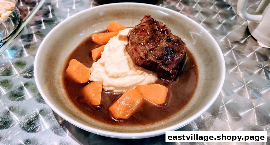 A hearty dish featuring braised meat, creamy mashed potatoes, and carrots in rich gravy.