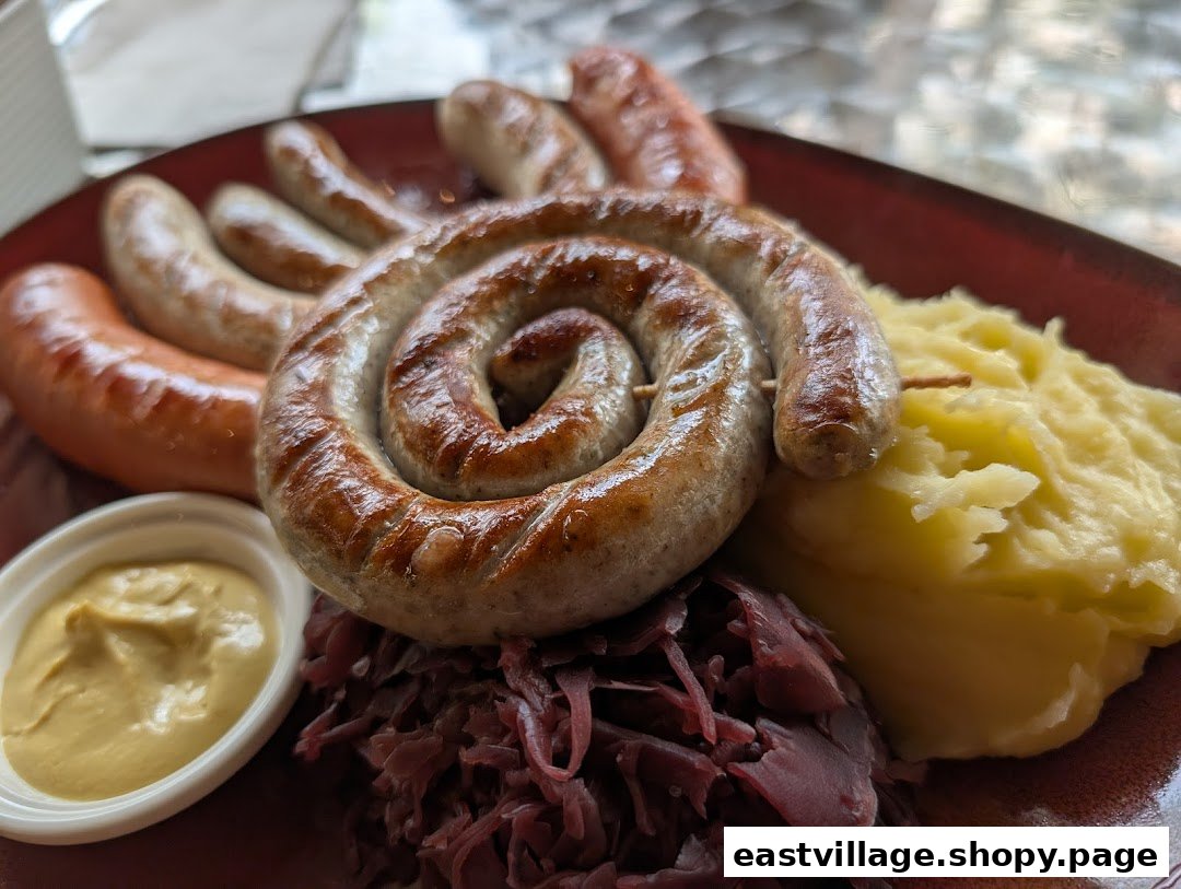 A plate of grilled sausages, including a coiled one, served with mashed potatoes, red cabbage, and mustard.