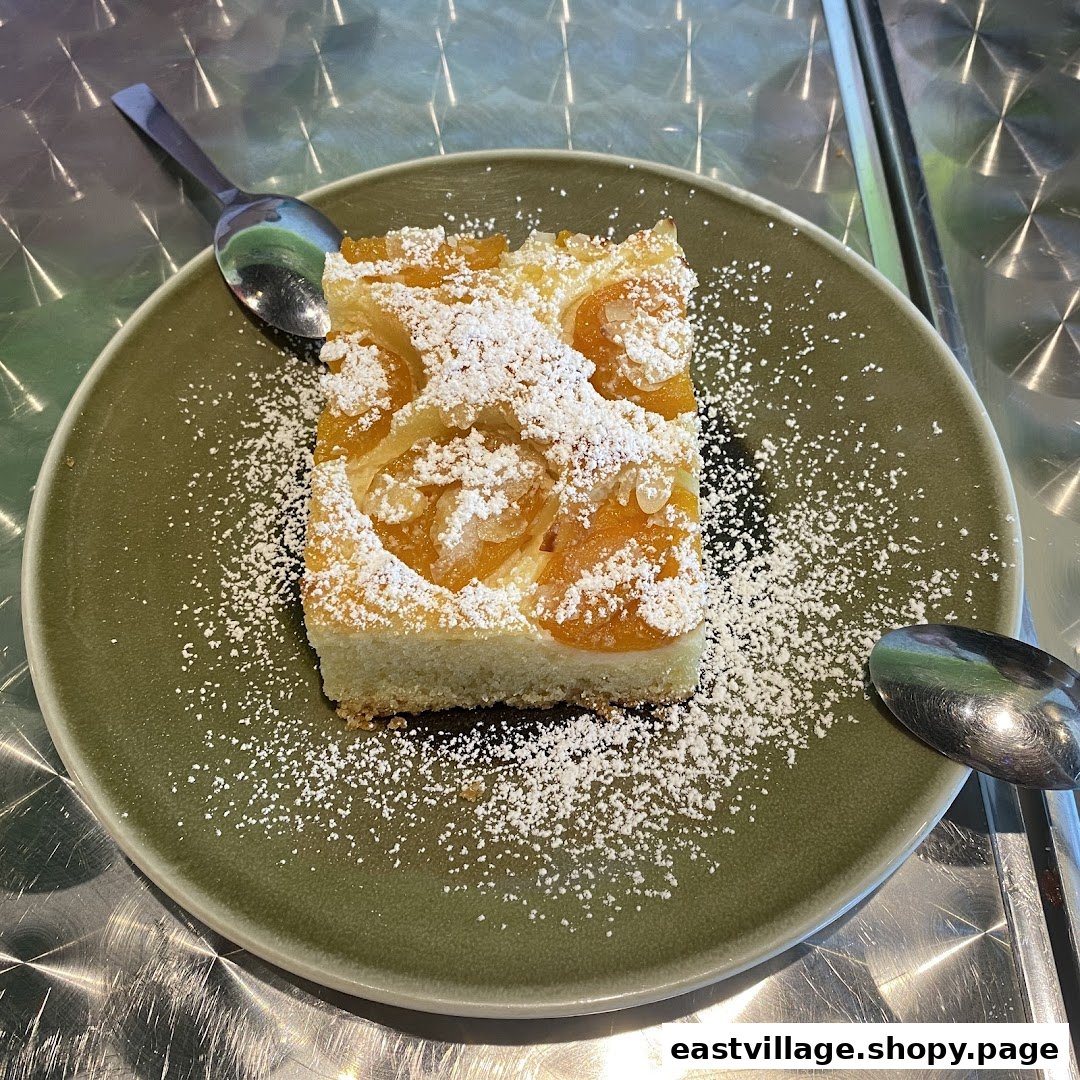 A delicious slice of apricot cake, dusted with powdered sugar, served on a green plate.