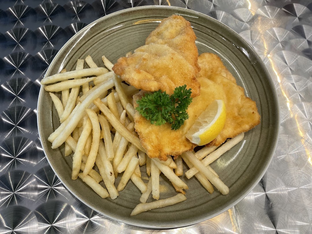 Golden fried schnitzel served with crispy fries, fresh parsley, and a lemon wedge.