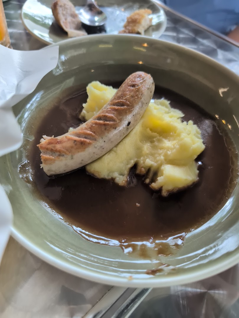 A hearty plate featuring a grilled sausage, creamy mashed potatoes, and rich brown gravy.