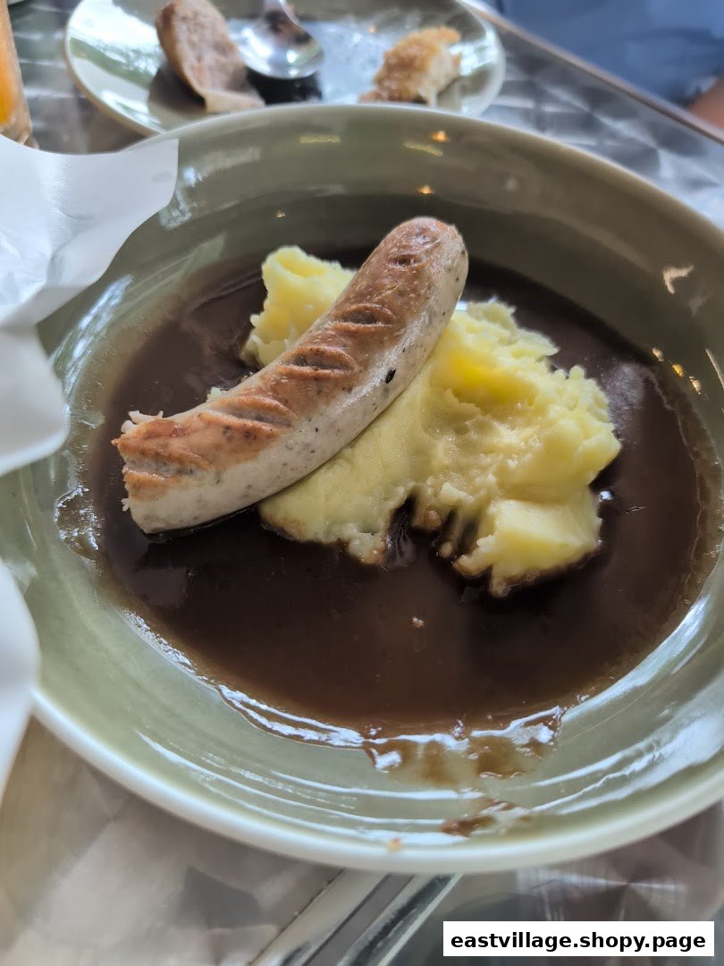 A hearty plate featuring a grilled sausage, creamy mashed potatoes, and rich brown gravy.