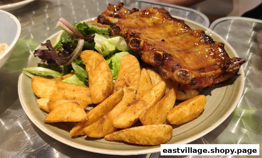 A delicious plate of glazed ribs served with crispy potato wedges and a fresh side salad.